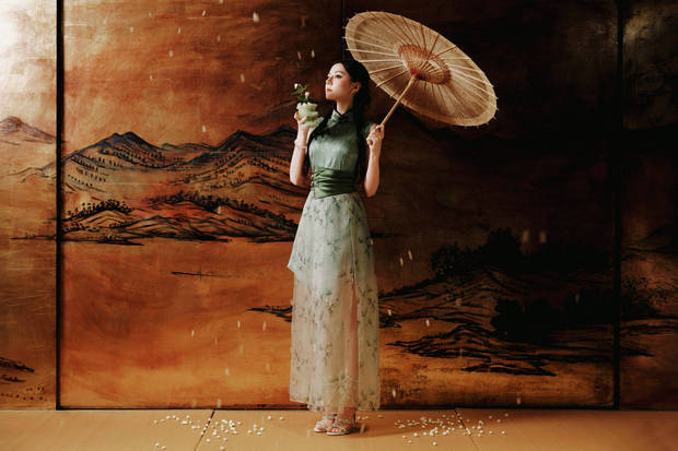 迪丽热巴撑伞拍照，一袭翠绿旗袍裙清新怡人。