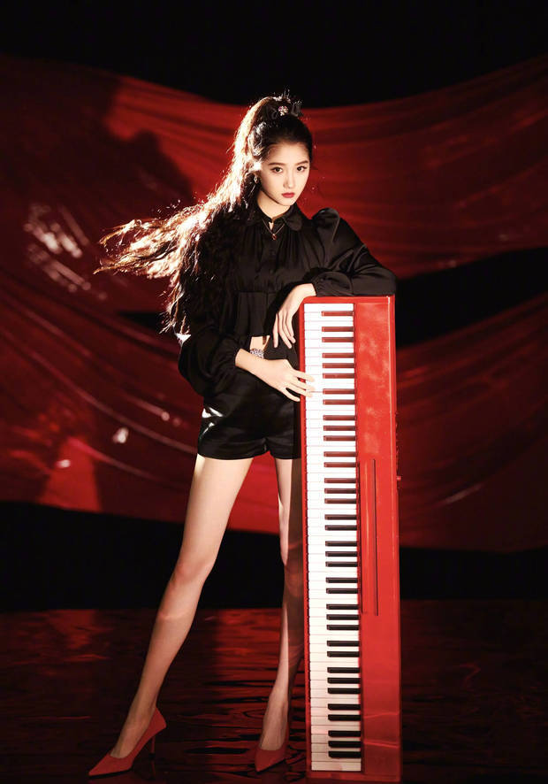 关晓彤倚靠红色钢琴，眼神坚定，尽显飒爽魅力。